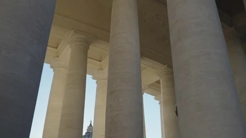 Massive stone marble columns frame ornate architecture and distant church dome Stock Footage 347973892