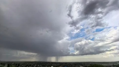 Massive storm cloud with visible rain over landscape Stock Photos