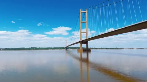 Massive suspension bridge spans wide river under clear sky Vidéo 343520730