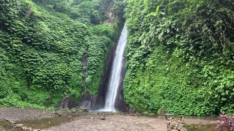 Massive waterfall with lush greenery and bench on Bali island Stock Footage 339932579