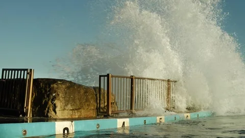 Massive wave hits a rock next to a public pool slow motion 4K Video stock 246021002