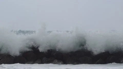 Massive waves spash over wavebreaker Stock Footage 186492144