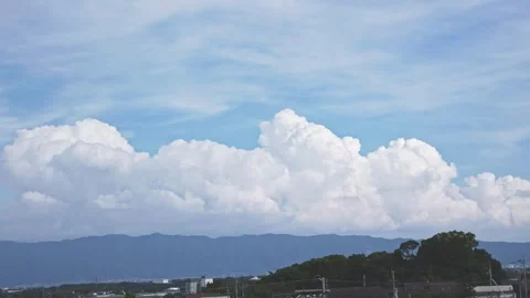 Massive white cumonimbus clouds over distant mountains under blue summer sky Stock Footage 338398561