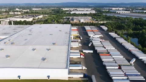 Massive white warehouse rooftop borders dozens of parked semi trailers lined Stock Footage 340970858