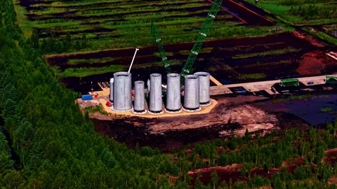 Massive wind-turbine tower sections stand in rows on a remote construction Stock Footage 325570913