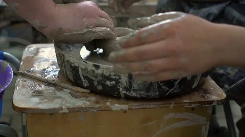 Master and apprentice making a ceramic bowl on pottery wheel in a workshop Stock Footage 76165442