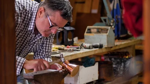 The master on an anvil hammering on a copper product with a hammer Stock Footage 124473959
