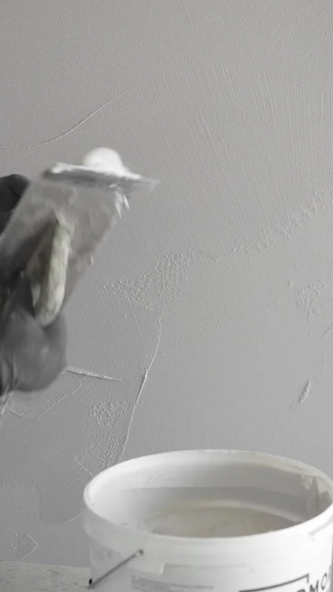 Master  applies gray decorative plaster to the wall with a spatula and trowel Stock Footage 317409479