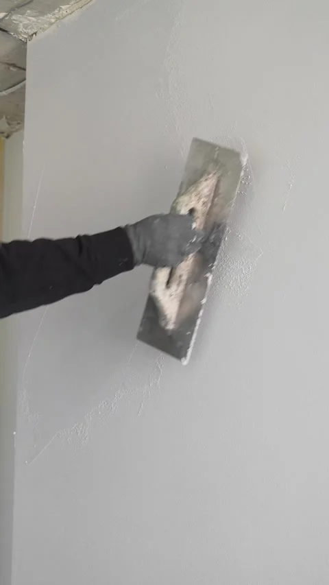 Master  applies gray decorative plaster to the wall with a spatula and trowel Video stock 317409493