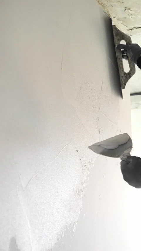 Master  applies gray decorative plaster to the wall with a spatula and trowel Video stock 317409496