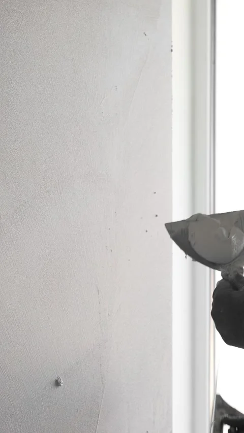 Master  applies gray decorative plaster to the wall with a spatula and trowel Video stock 317409502