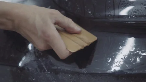 The master applies a protective layer on the surface of the car Stock Footage 93604313