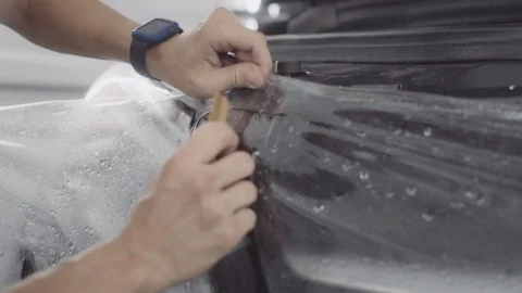 The master applies a protective layer on the surface of the car Stock Footage 93604410