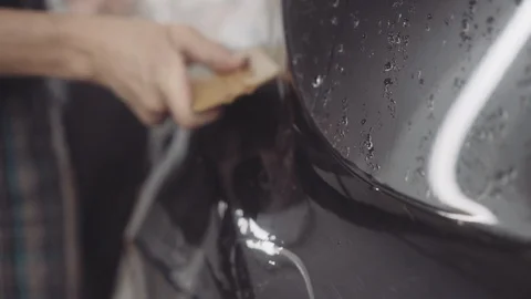 The master applies a protective layer on the surface of the car Stock Footage 93604455
