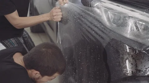The master applies a protective layer on the surface of the car Stock Footage 93604473