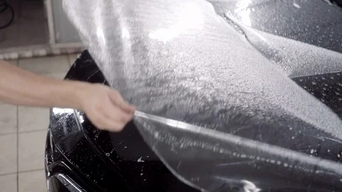 The master applies a protective layer on the surface of the car Stock Footage 93621052