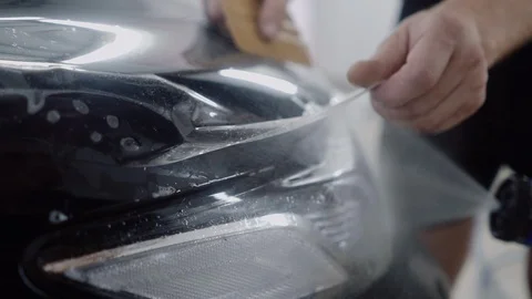 The master applies a protective layer on the surface of the car Stock Footage 93622976
