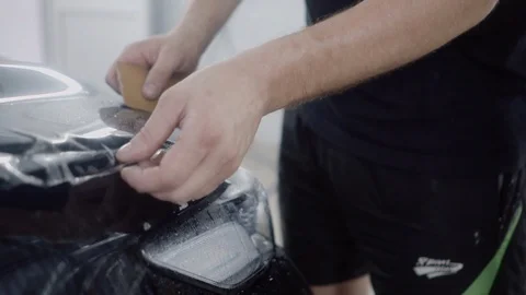 The master applies a protective layer on the surface of the car Stock Footage 93623065