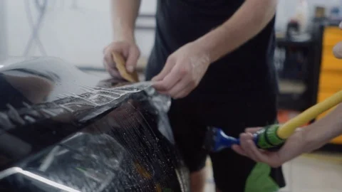 The master applies a protective layer on the surface of the car Stock Footage 93623170