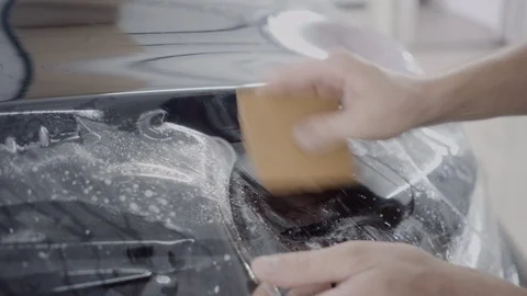The master applies a protective layer on the surface of the car Stock Footage 93626403