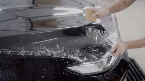 The master applies a protective layer on the surface of the car Stock Footage 93626673