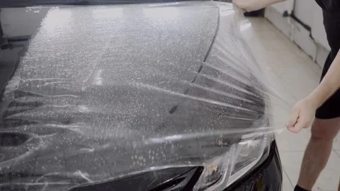The master applies a protective layer on the surface of the car Stock Footage 93626765