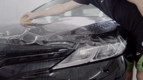 The master applies a protective layer on the surface of the car Stock Footage 93627033
