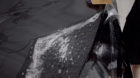 The master applies a protective layer on the surface of the car Stock Footage 93627303