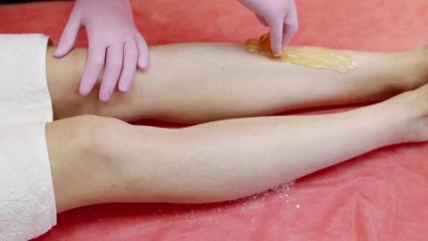 A master applies a shugaring paste to a woman's leg to remove hair Video stock 138388850