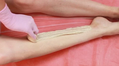 A master applies a shugaring paste to a woman's leg Stock Footage 138402703