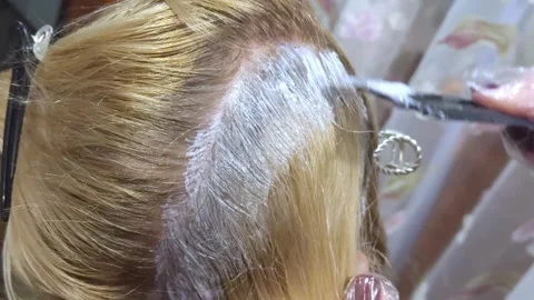 Master applying dye to the roots of a woman's light hair with a brush. Clos.. Stock Footage 320709303