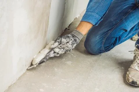 Master is applying white putty on a wall and smearing by putty knife in a room Stock Photos