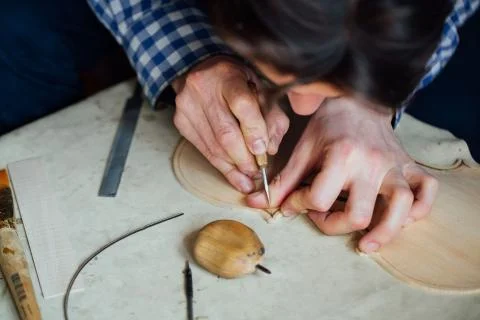 Master artisan luthier working on the creation of a violin. painstaking detailed Stock Photos
