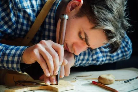 Master artisan luthier working on the creation of a violin. painstaking detailed Stock Photos