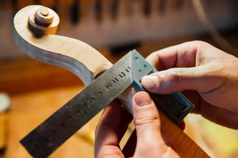 Master artisan luthier working on creation of a violin scroll. detailed work on Stock Photos