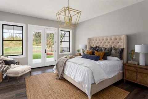 Master bedroom interior in new luxury home. French doors lead outside Stock Photos
