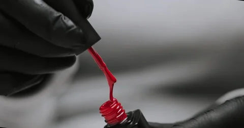 Master in black gloves holds red nail polish with an open bottle Stock Footage 149367486