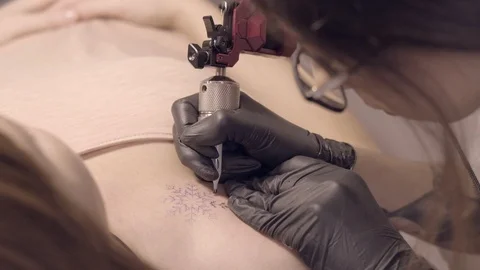 Master in black gloves makes a tattoo snowflake girl Stock Footage 122985293