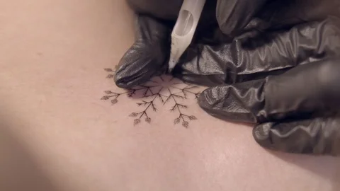 Master in black gloves makes a tattoo snowflake girl Stock Footage 122985674