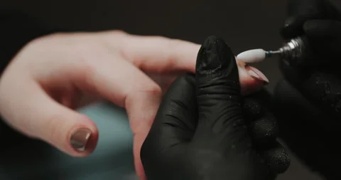 Master in black gloves making manicure using electric equipment for nails. Video stock 149365336
