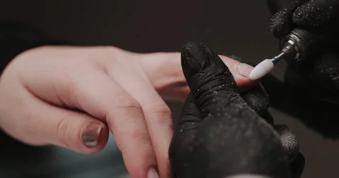 Master in black gloves making manicure using electric equipment for nails. Video stock 149365567