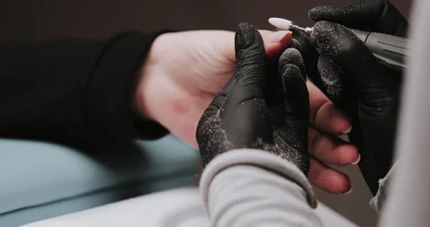Master in black gloves making manicure using electric equipment for nails. Video stock 149365794