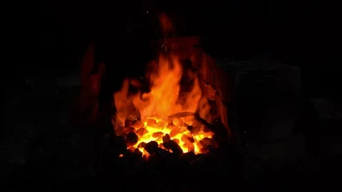 The master blacksmith flattens the coal seam with a metal poker Stock Footage 152340608