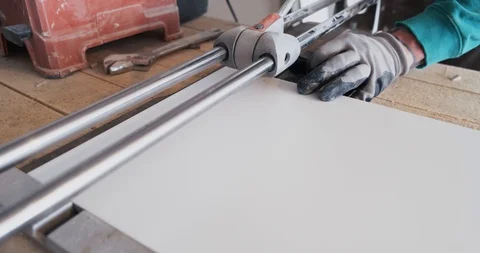 Master builder cuts ceramic tiles with sharp knife, confident movements, cutting Stock Footage 129839250