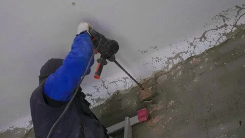 The master builder drills a hole in the wall during the repair work in the room. Stock Footage 279230638