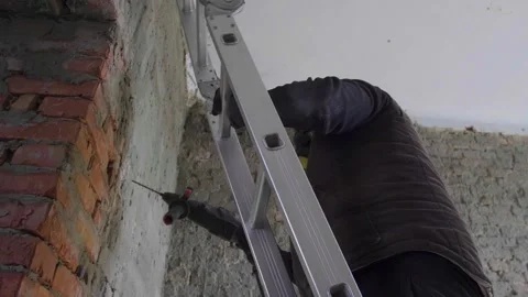 The master builder drills a hole in the wall during the repair work in the room. Stock Footage 279230704