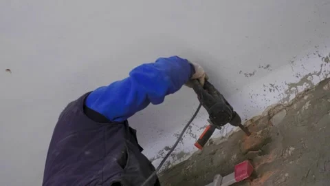 The master builder drills a hole in the wall during the repair work in the room. Stock Footage 279230832