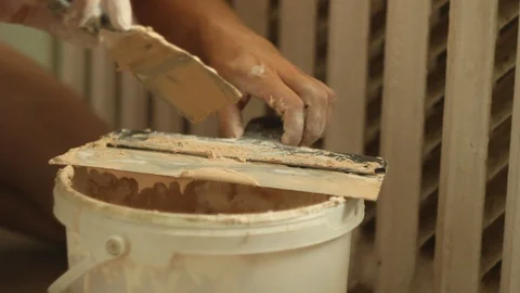 Master builder picks up a plaster spatula from a plastic bucket Stock Footage 106356308