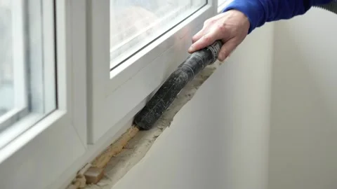 Master builder vacuums window and window sill with vacuum cleaner before renovat Stock Footage 317394745