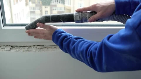 Master builder vacuums window with vacuum cleaner before renovation Stock Footage 317395045